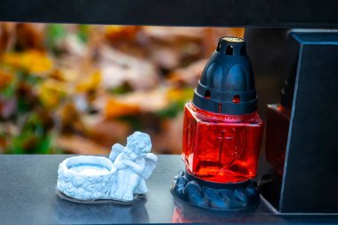 Sonbaharda yapraklı bir mezar ışığı, eski mezarlıkta klasik lambalar.