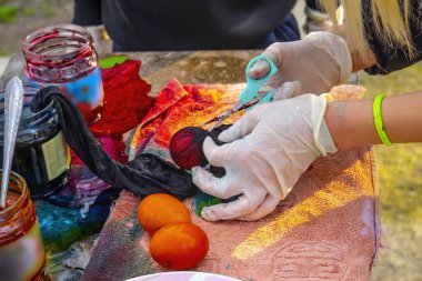 Paskalya Ailesi gelenekleri. Annem Paskalya tatili için yumurtaları boyayla süslerken mutfak masasında birlikte oturur, seçici bir şekilde.