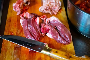 Tahtadaki çiğ koyun kalbi eti bıçakla ve baharatla kesmek için..