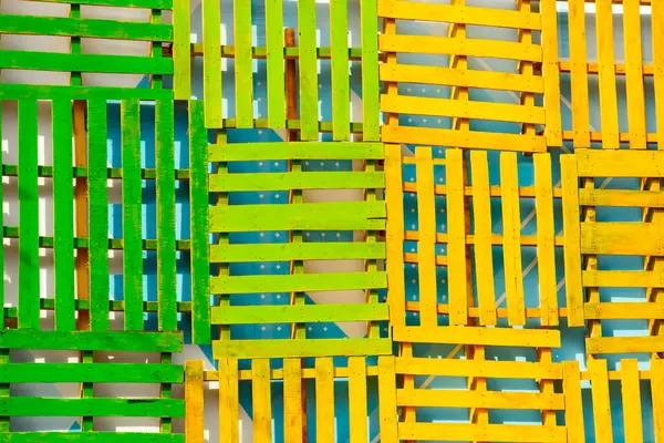 Wooden pallets of different colors and shapes lie in a row in a top view.
