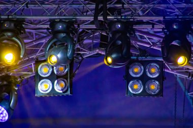 Hareket eden far cihazları çelik kirişlere kenetlenir. Konser için profesyonel ışıklandırma ekipmanı kurulumu.