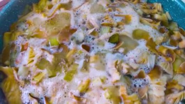 Mutfaktaki çorba hazırlama sırasında metal tavada çeşitli baharatlarla pişirilen iştah açıcı mantarların üst görüntüsü. Kahverengi mantarlarla dolu kaynar kase.