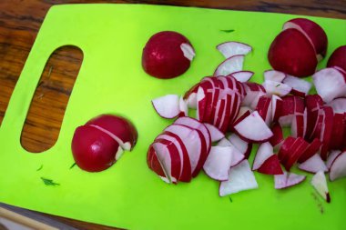 Sliced radishes on a green plastic cutting board