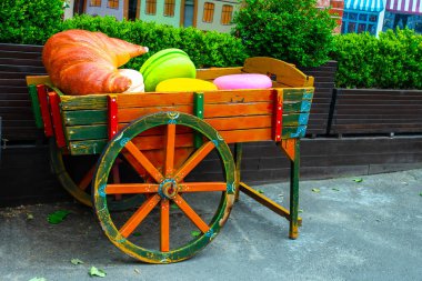 Sokaklarda kruvasan ve çöreklerle süslü ahşap bir araba.