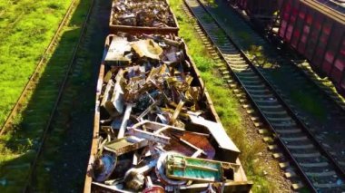 Demiryolu yük vagonunun üstünde eski paslı siyah metal hurda çöpleriyle dolu fabrika geri dönüşümü için. Çelik atık toplama, imha lojistiği.