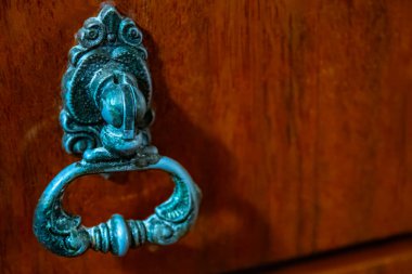 Önünde ahşap bir gardırop çekmecesi, metal saplı. Kapı tokmakları