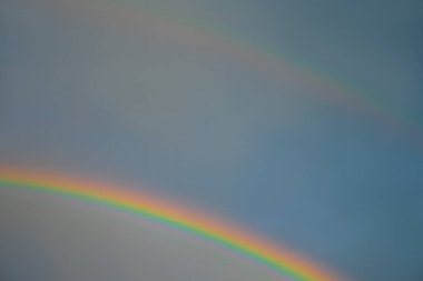 Mavi gökyüzü ve gökkuşağı ile bulutlar.