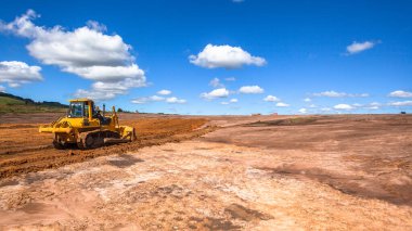 Kırsal bölgedeki yeni sanayi projesi, büyük fabrika deposu inşaatı için toprağı açık platoda hareket ettiren buldozer makineleri tarafından dönüştürüldü..