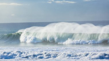 Deniz suyundan oluşan dalgalı okyanus duvarı enerjiyi sahile doğru çekiyor. Yakın plan bir fotoğraf..