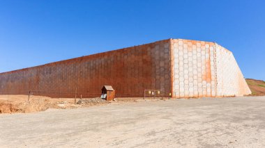 Construction New development infrastructure large concrete retaining inter locking wall corner set in position a closeup on large puzzle pieces against blue sky.