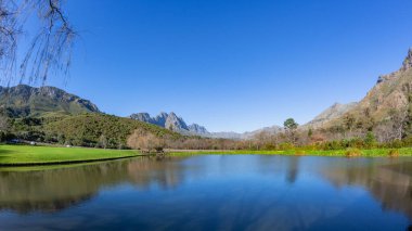 Göl sularına bakan manzaralı vadi dağlarına bakan kar mavi gökyüzüne düşer..