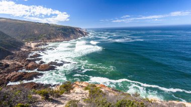 Rocky Cliffs Mavi gökyüzü dalgaları uzak ufuklar beyaz bulutlar manzaralı bir doğa manzarası.