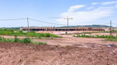 Kırsal kesimde yeni bir alışveriş merkezi inşaatı. Beton kolonlar, vinç, iskele ve kırsal kesimde toprak işleri..