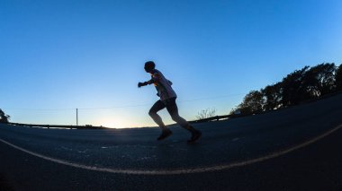 Maraton koşucuları siluet sabah şafak vakti şafak sökerken ultra mesafe yarışında yokuş yukarı koşuyor.