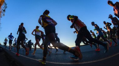 Maraton koşucuları siluet sabah şafak vakti şafak sökerken ultra mesafe yarışında yokuş yukarı koşuyor.