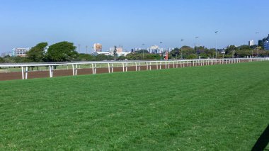 At yarışı sahası çimen bölgesi ve polyester kum yolları düz mavi gökyüzü manzarası.