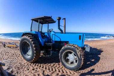 Sahil teknesi traktörü boş karavan balıkçılarıyla denize indiriyor. Balıkçılık sabahı okyanus ufkunda mavi manzara..