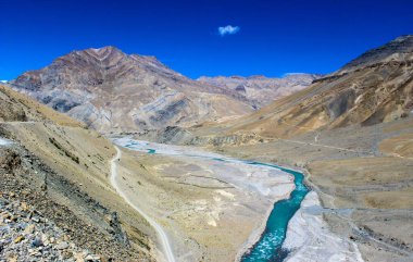 Hindistan 'ın uzak Himalaya bölgesinde engebeli dağları, dolambaçlı yolları ve berrak mavi gökyüzü ile Spiti Vadisi' nin nefes kesici manzaraları..