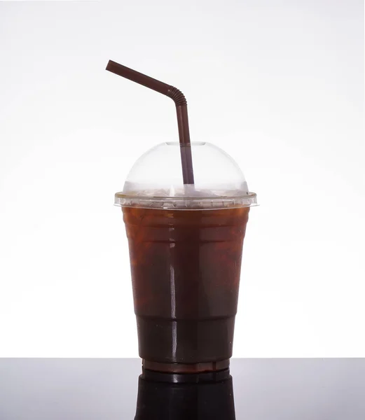 Ice americano coffee in takeaway glass, on white background and black glass floor.