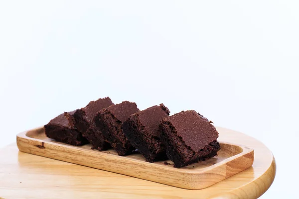 Pieces of fresh chocolate brownie on wooden plate on white background. Stack of fudgy chocolate brownies on white background, homemade bakery and dessert.