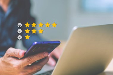 Bir e-posta ikonu ve grup insanlarının memnuniyet kavramı üzerine yıldız ifadeli el ele tutuşan akıllı telefon. Reytingler, incelemeler, anket cevapları, bilgiler. Bilgisayarlı telefon kullanan adam. 