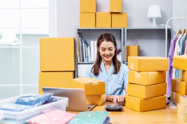 Küçük işletme girişimcisi KOBİ 'ye serbest olarak başlayan genç işletme sahibi kadın, müşterilerden sipariş aldı ve ürünlerin karton kutu paketlemedeki fiyatlarını hesapladı..