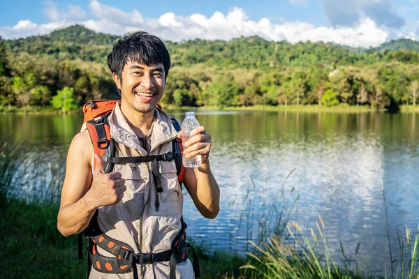Красивый Молодой Азиатский Мужчина Путешественник Отдыхает Природе Держа Руках Бутылку — стоковое фото