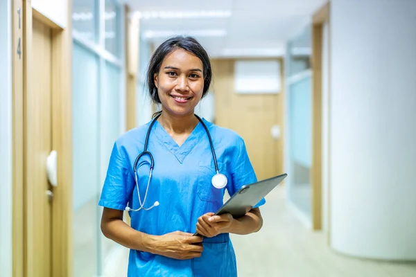 클리닉에 파란색 유니폼을 디지털 태블릿을 이시아 간호사나 의사의 종사자들 — 스톡 사진