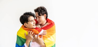 Erkekler evde vakit geçirir, mutlu Asyalı eşcinsel çiftin portresi kucaklaşır ve Igbt renkli gökkuşağı bayrağı altında sevgilerini gösterirler. LGBT ve aşk konsepti.