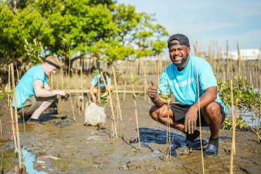 Afrikalı Amerikalı erkekler, çevre koruma ve ekoloji için mangrov ormanlarına ağaç dikmeye, küresel ısınmayı azaltmaya ve hayır işlerine yardım etmeye gönüllü.