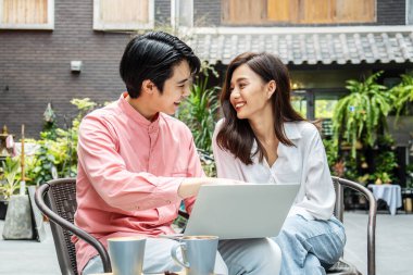 Kafe 'de kahve molası sırasında internette sörf yapan modern bir çift, kahve içip internetten alışveriş yapan mutlu bir erkek ve kadın veya restoranda dizüstü bilgisayarda proje planlamayı tartışan bir çift.