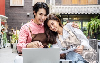 Kafe 'de kahve molası sırasında internette sörf yapan modern bir çift, kahve içip internetten alışveriş yapan mutlu bir erkek ve kadın veya restoranda dizüstü bilgisayarda proje planlamayı tartışan bir çift.