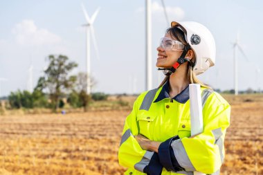 İş çıkışı rüzgâr türbininde çalışan beyaz üniformalı bir kadının portresi. Neşeli gülümsemeler ve olumlu ifadelerle çalışmalara bakın. İş başarısı.