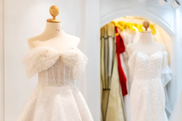 Beautiful wedding dresses, bridal dress hanging on hangers and mannequin in studio. Fashion look.