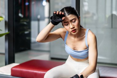 Antrenmandan sonra spor salonundaki genç Asyalı kadının portresi. Beden eğitiminden sonra terli ve nefes darlığı çekiyor. Enerji yakmak ya da spor yapmak için egzersiz yapıyor..