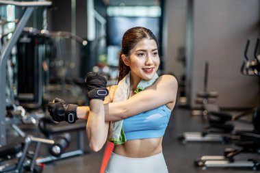 Aktif genç Asyalı kadın spor salonunda yoğun antrenmandan önce vücudunu ısıtıyor. Genç bayanın yaptığı temel spor salonları.