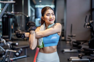 Aktif genç Asyalı kadın spor salonunda yoğun antrenmandan önce vücudunu ısıtıyor. Genç bayanın yaptığı temel spor salonları.