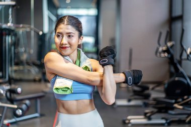 Aktif genç Asyalı kadın spor salonunda yoğun antrenmandan önce vücudunu ısıtıyor. Genç bayanın yaptığı temel spor salonları.