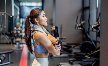 Aktif genç Asyalı kadın spor salonunda yoğun egzersizden önce ısınıyor. Genç bayanın yaptığı temel spor egzersizleri.