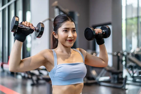 Ağırlık antrenmanı, arka planda ekipmanla ağırlık kaldıran Asyalı genç bir kadın güçlü vücut şekline sahip spor giyim kız antrenmanı, fotokopi alanı olan Asya yaşam tarzı.