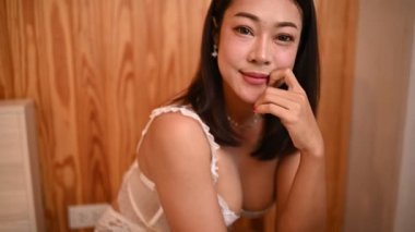 Asyalı seksi kadın portresi. Yatak odasında beyaz elbise giy.