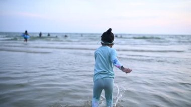 Asyalı kız eğlencesine denizde oynuyor. Aileyle yaz tatili. Çocuk sömestr tatili aktiviteleri