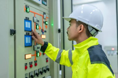 Elektrik mühendisi kontrol odasındaki elektrik dağıtım kabinesinde voltajı kontrol ediyor. Yıllık önleyici bakım, Tayland Elektrikçisi.
