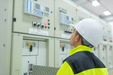 Elektrik mühendisi kontrol odasındaki elektrik dağıtım kabinesinde voltajı kontrol ediyor. Yıllık önleyici bakım, Tayland Elektrikçisi.
