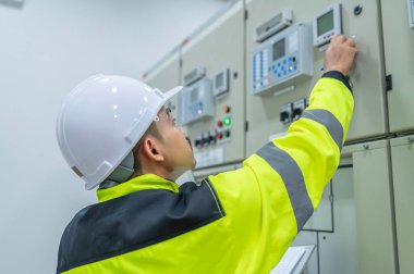 Elektrik mühendisi kontrol odasındaki elektrik dağıtım kabinesinde voltajı kontrol ediyor. Yıllık önleyici bakım, Tayland Elektrikçisi.