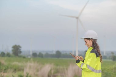 Kadın mühendis, Tayland 'daki dağda rüzgar türbini tarım güç jeneratörü istasyonunda çalışıyor ve raporu tutuyor.