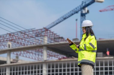 Tayland 'da büyük bir inşaat projesinin şantiyesinde çalışan Asyalı mühendis inşaat alanında fazla mesai yapıyor.