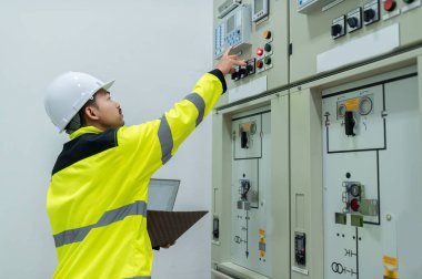 Elektrik mühendisi kontrol odasındaki elektrik dağıtım kabinesinde voltajı kontrol ediyor. Yıllık önleyici bakım, Tayland Elektrikçisi.