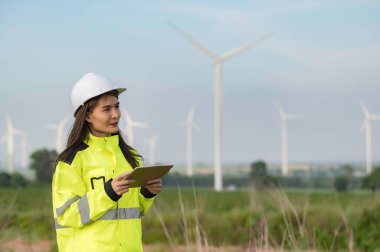 Kadın mühendis, Tayland 'daki dağda rüzgar türbini tarım güç jeneratörü istasyonunda çalışıyor ve raporu tutuyor.