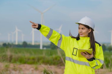 Kadın mühendis, Tayland 'daki dağda rüzgar türbini tarım güç jeneratörü istasyonunda çalışıyor ve raporu tutuyor.